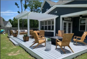 a deck with outdoor furniture and a pergola on back of home