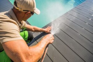 a technician cleaning off a poolside deck with a hose