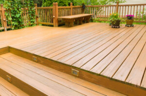 a wood deck with stairs, riser lights, railing, and a bench